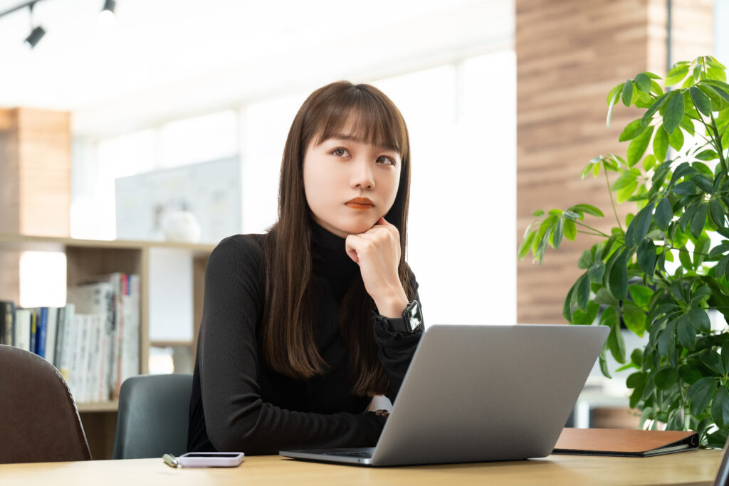 パソコンを触りながら考える女性