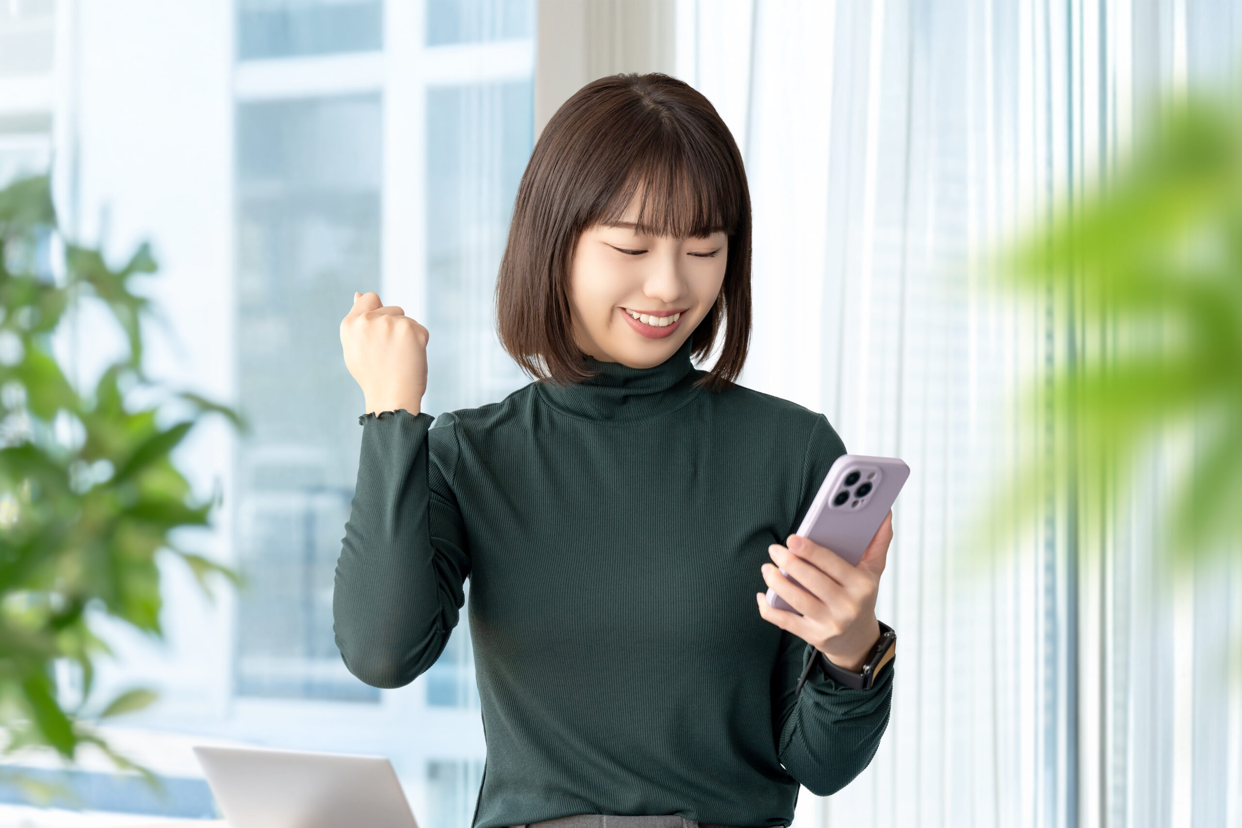 スマホを見てガッツポーズをする若い女性